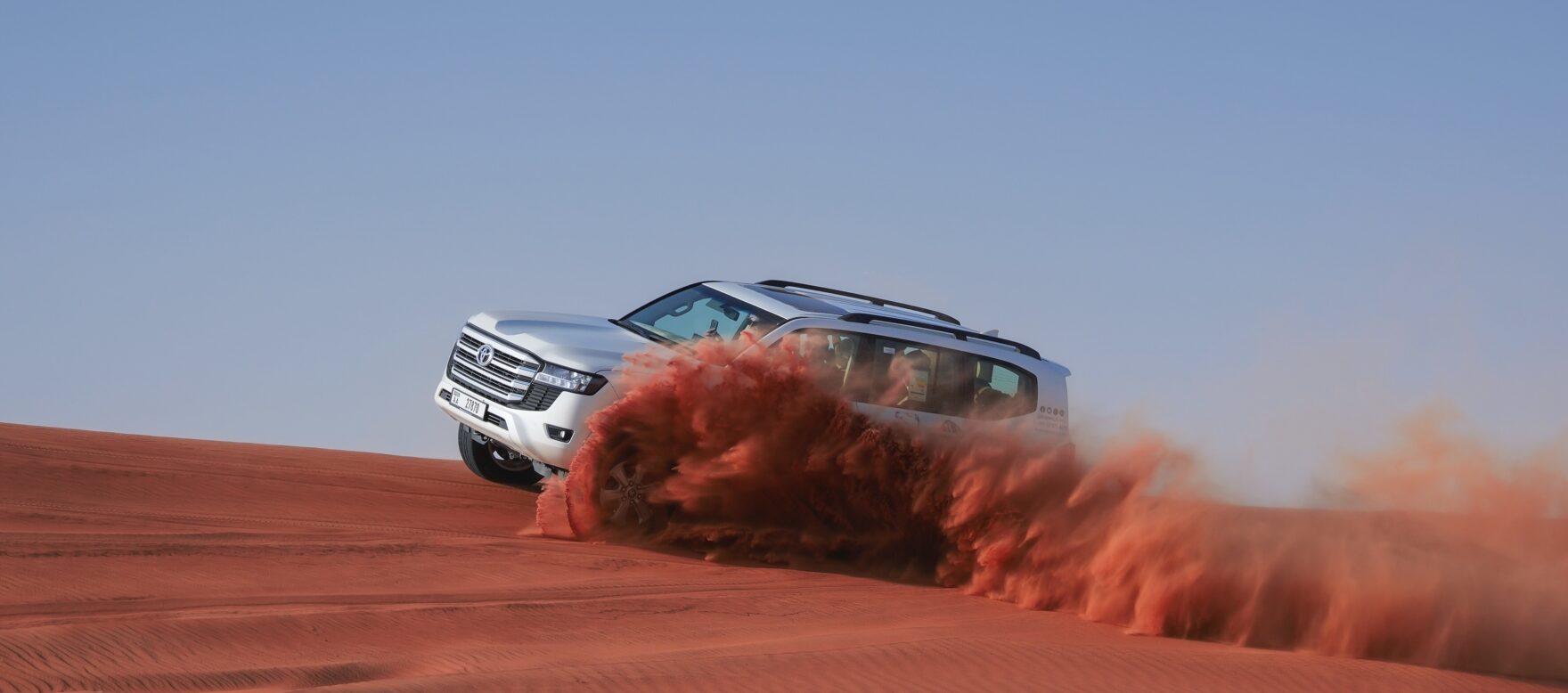 A line of premium 4x4 Land Cruisers parked on the Al Lahbab red dunes during a sunset stop, answering the user query: is desert safari worth it?